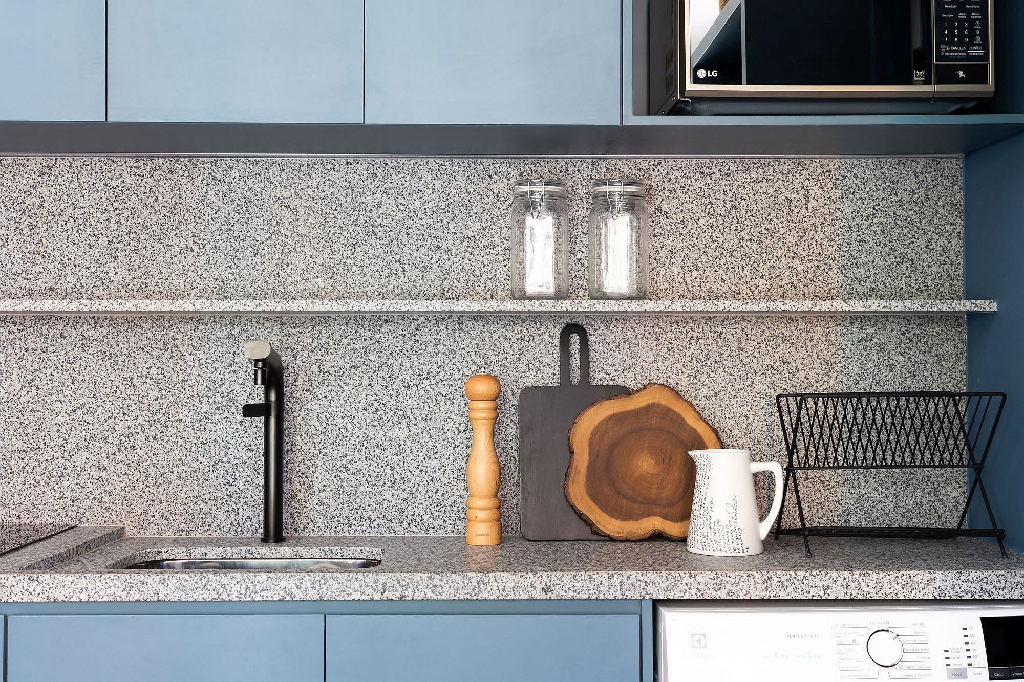 Closer look at the clean granite countertops and slim floating shelves in the blue contemporary kitchen