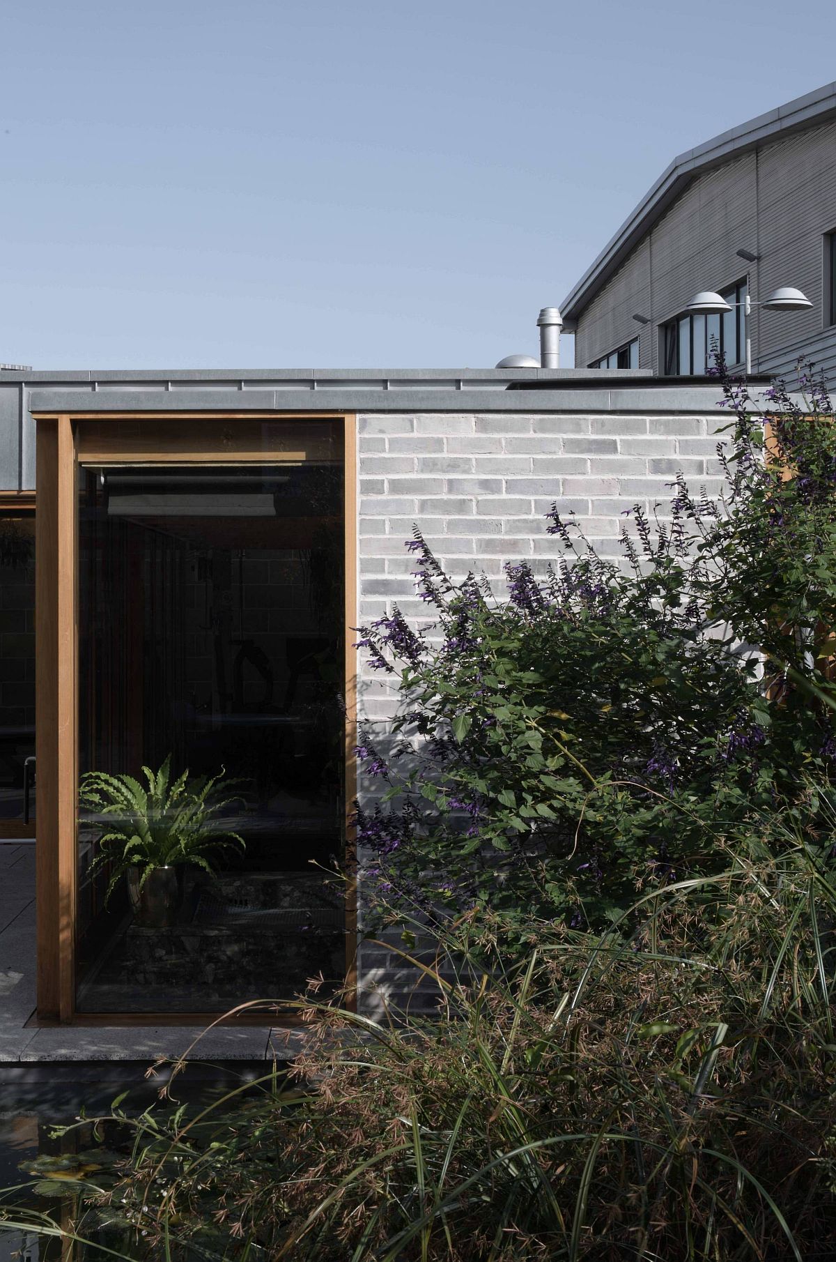 Exposed blockwork walls, wood and glass shpe the lovely backyard escape