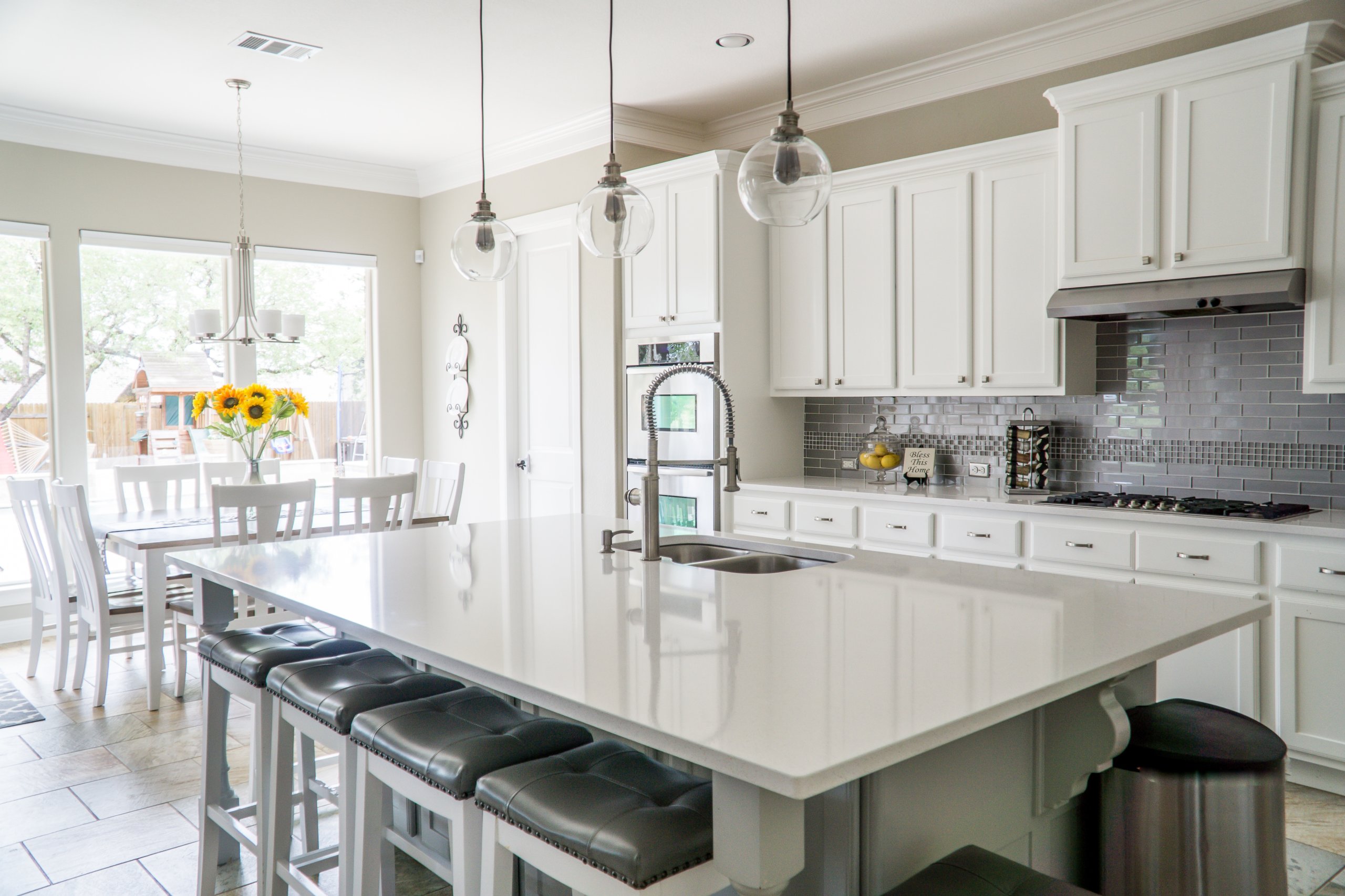 Kitchen interior with white cabinets, large island and white dining table and chairs