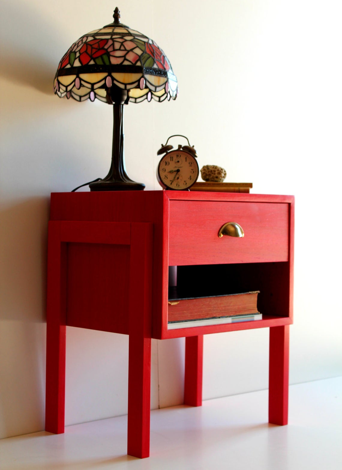 Lampshade and clock on top of a red drawer