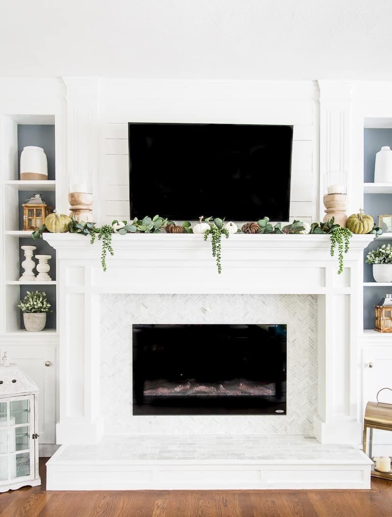 White fireplace with green and white decorations on the mantel