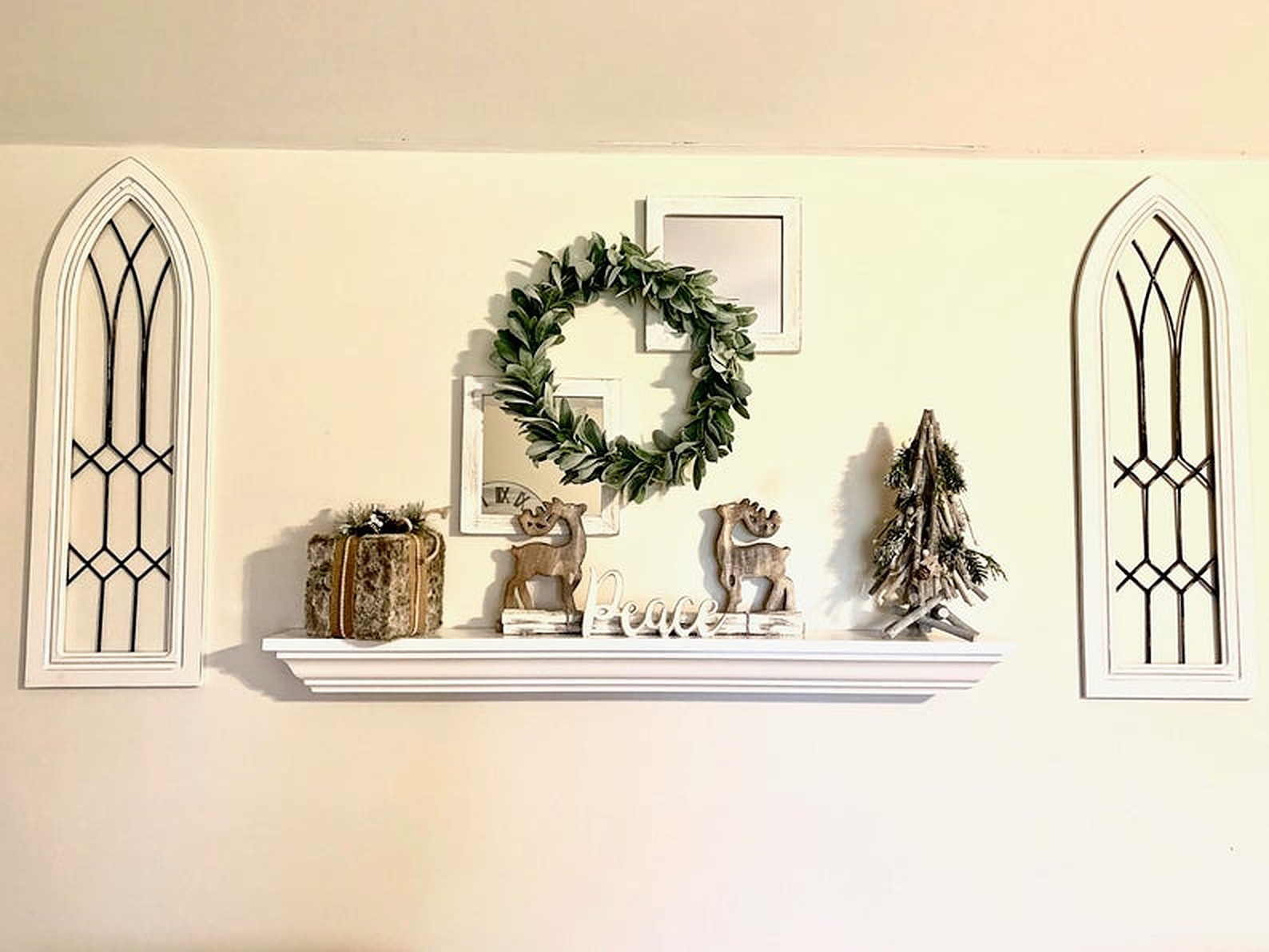 White floating mantel with green wreath and makeshift windows