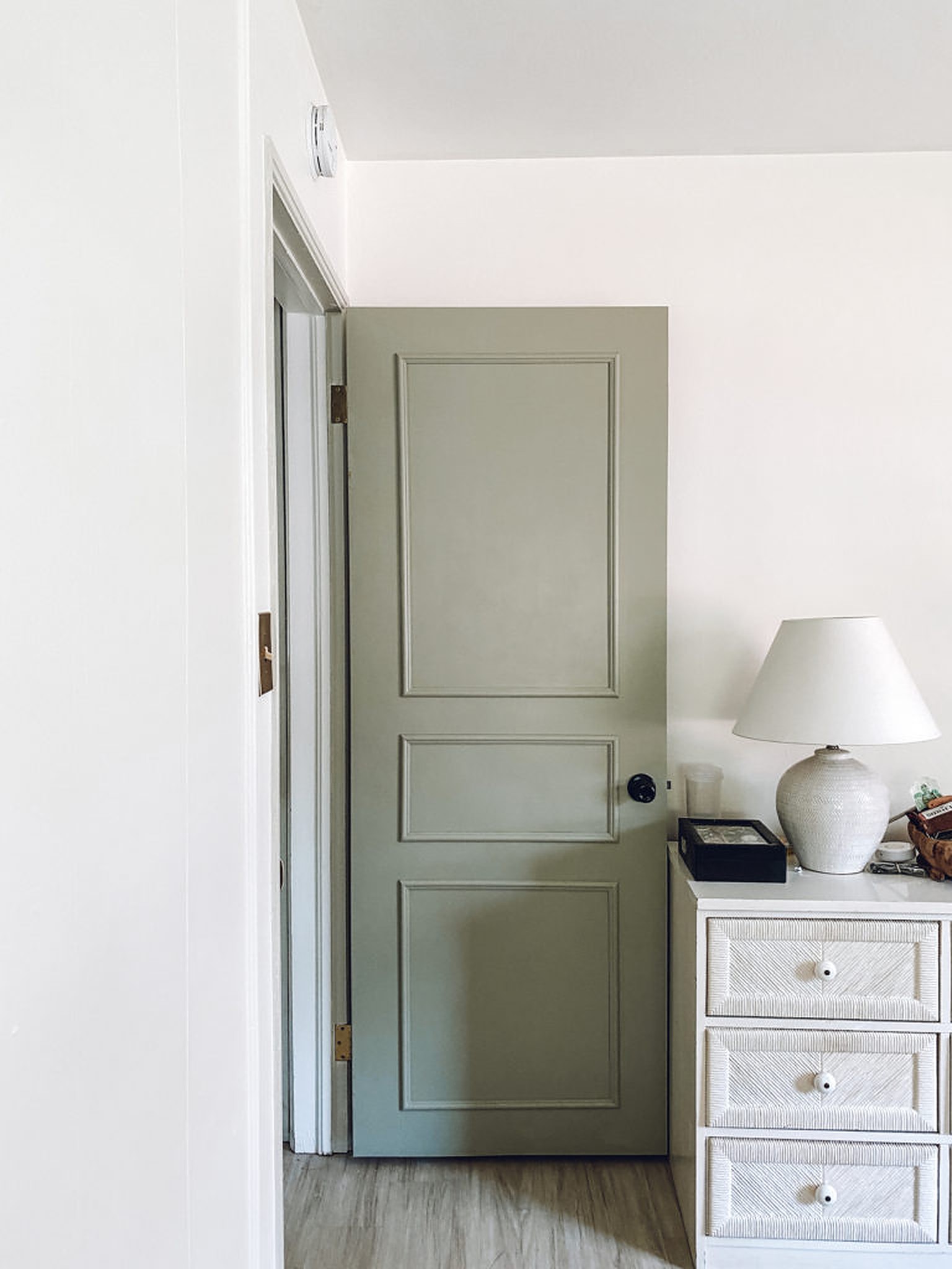 White lamp on white cabinet and an open door