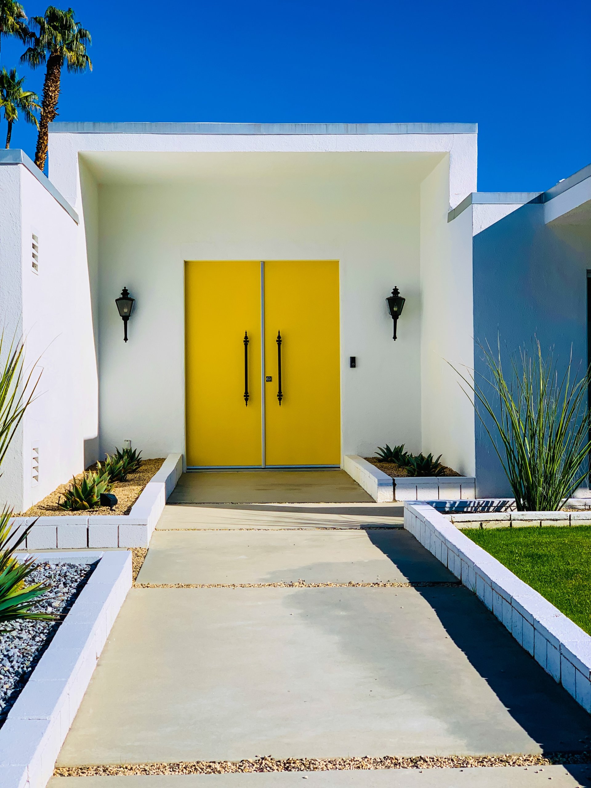 White wall with yellow door and black lamps