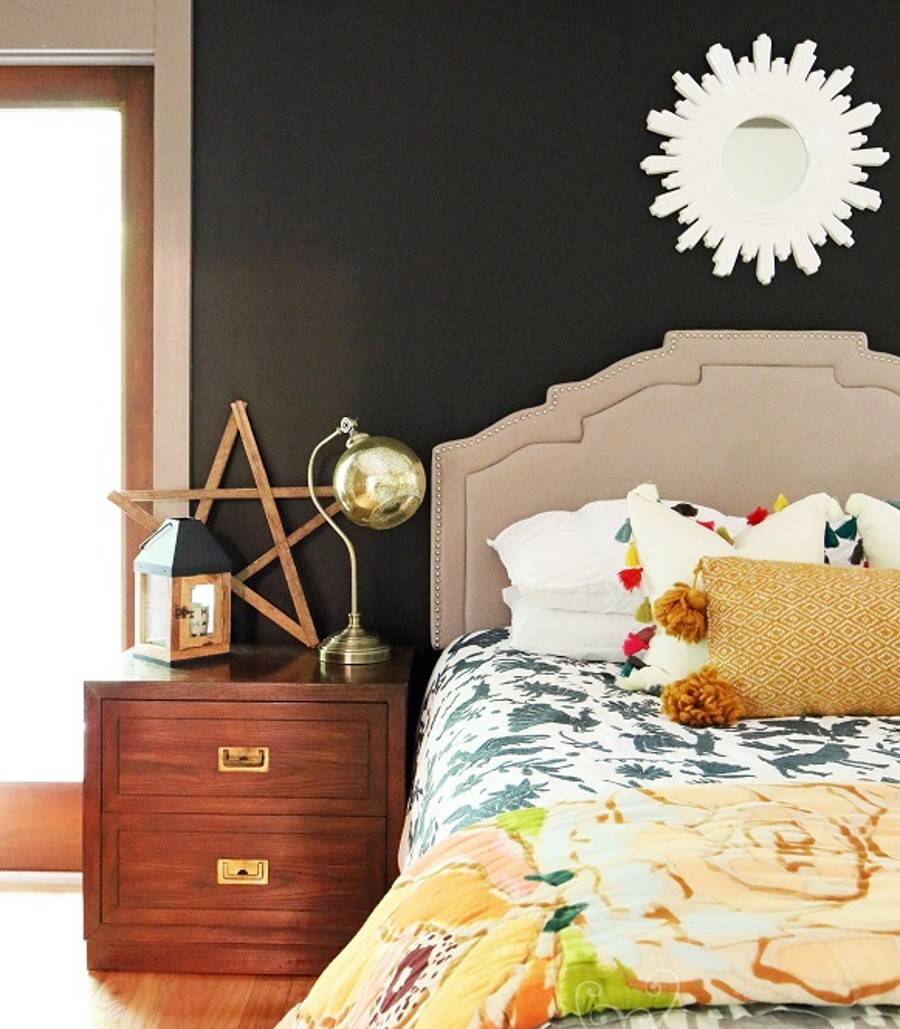 brightly colored master bed against black wall with white mirror mounted above headboard