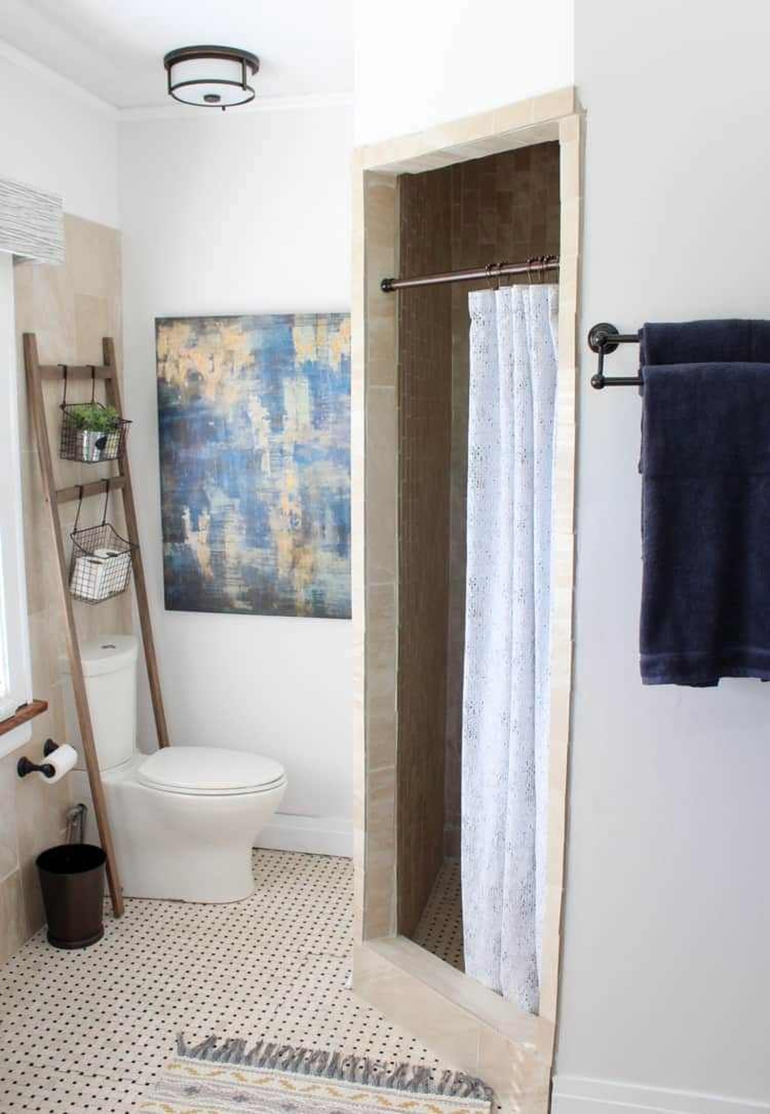 Bathroom with blue abstract painting and toiletries rack on a ladder