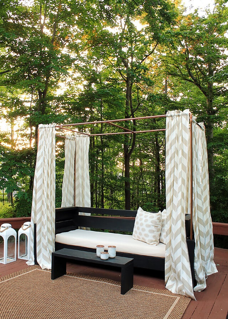 outdoor sofa with curtains hanging from copper pipes