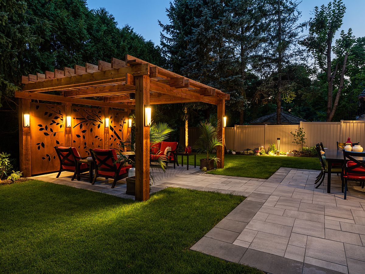 Custom wooden panels with apttern and warm lighting shape this tropical style pergola