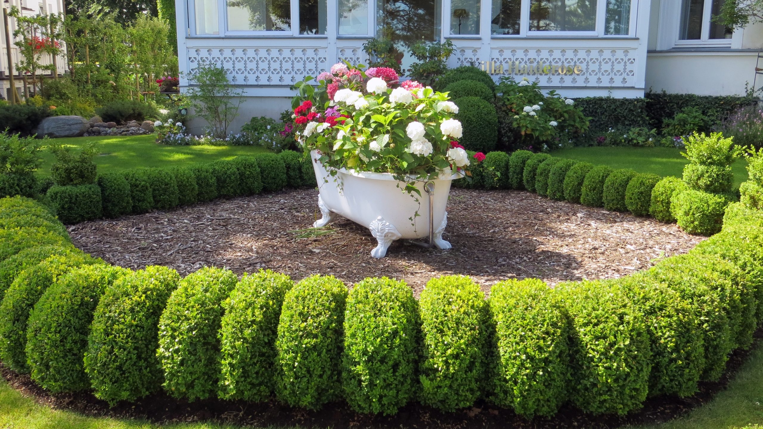 Flowers on a tub surrounded by well-maintened hedges