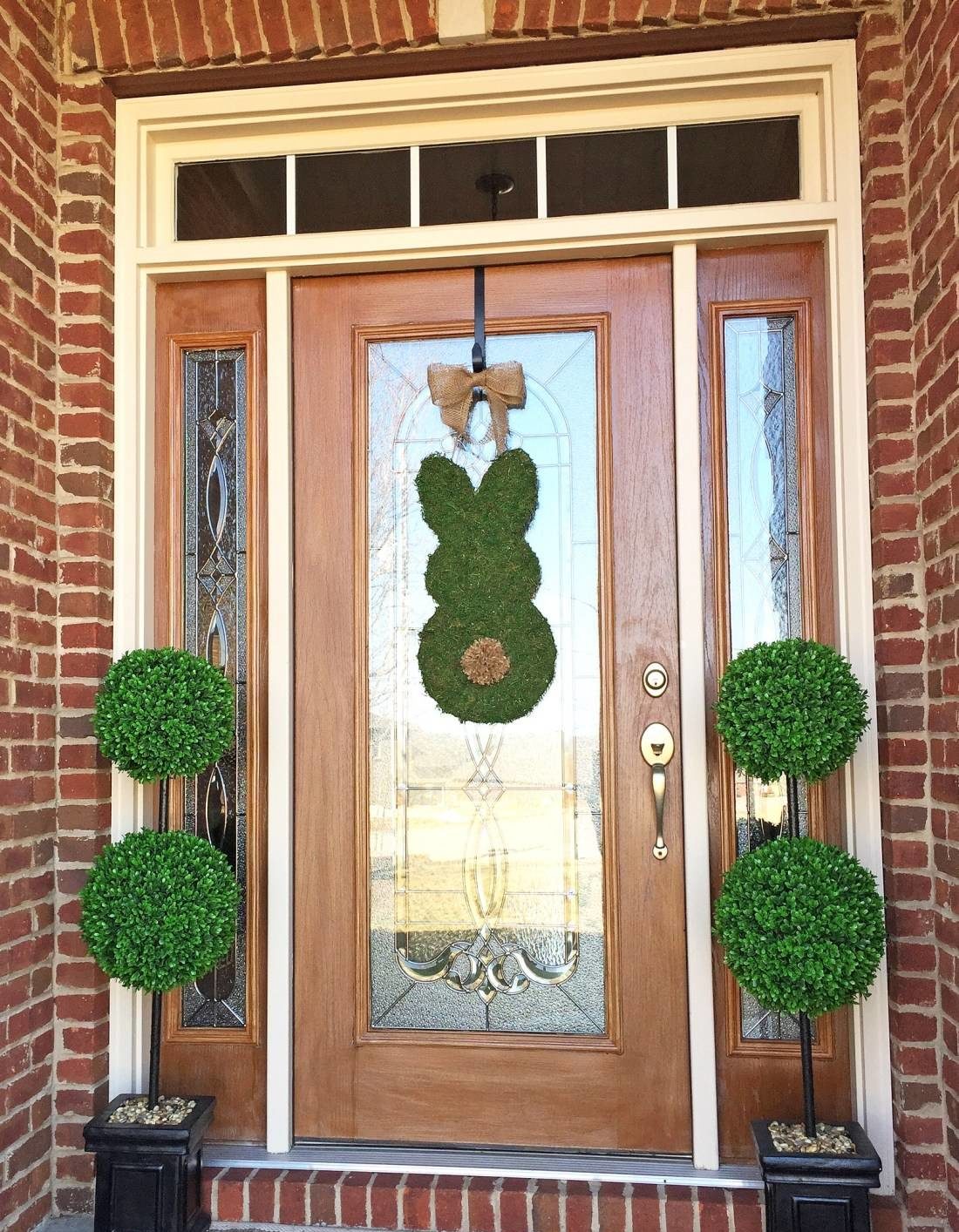 Moss bunny door decor with green potted plants on the sides