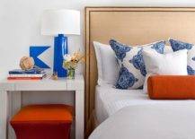 Contemporary bedroom with white bedding nightstand side lamp orange ottoman pillows