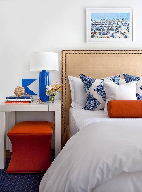 Contemporary bedroom with white bedding nightstand side lamp orange ottoman pillows