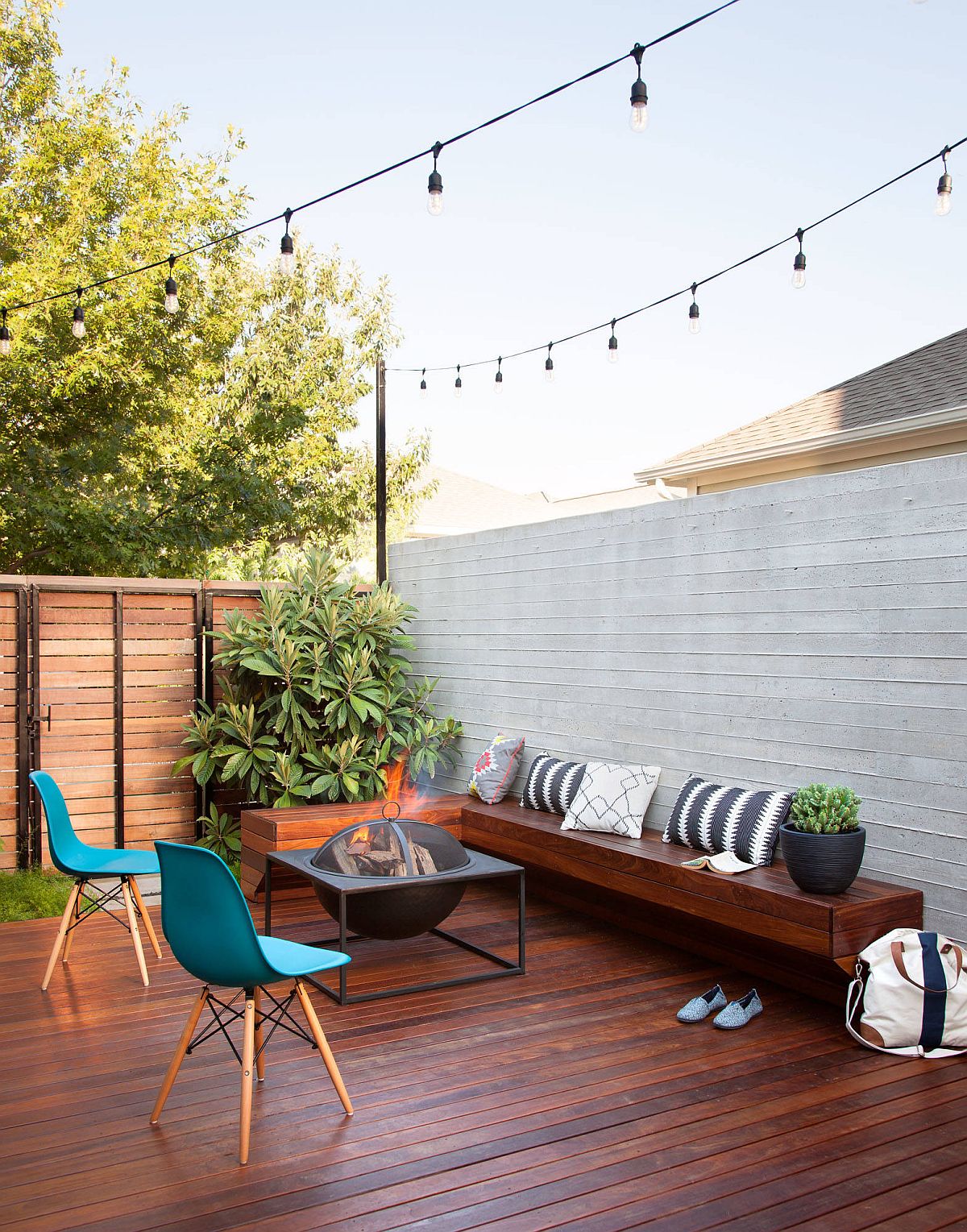 Private wooden deck design with fire pit, custom wooden bench and string lighting