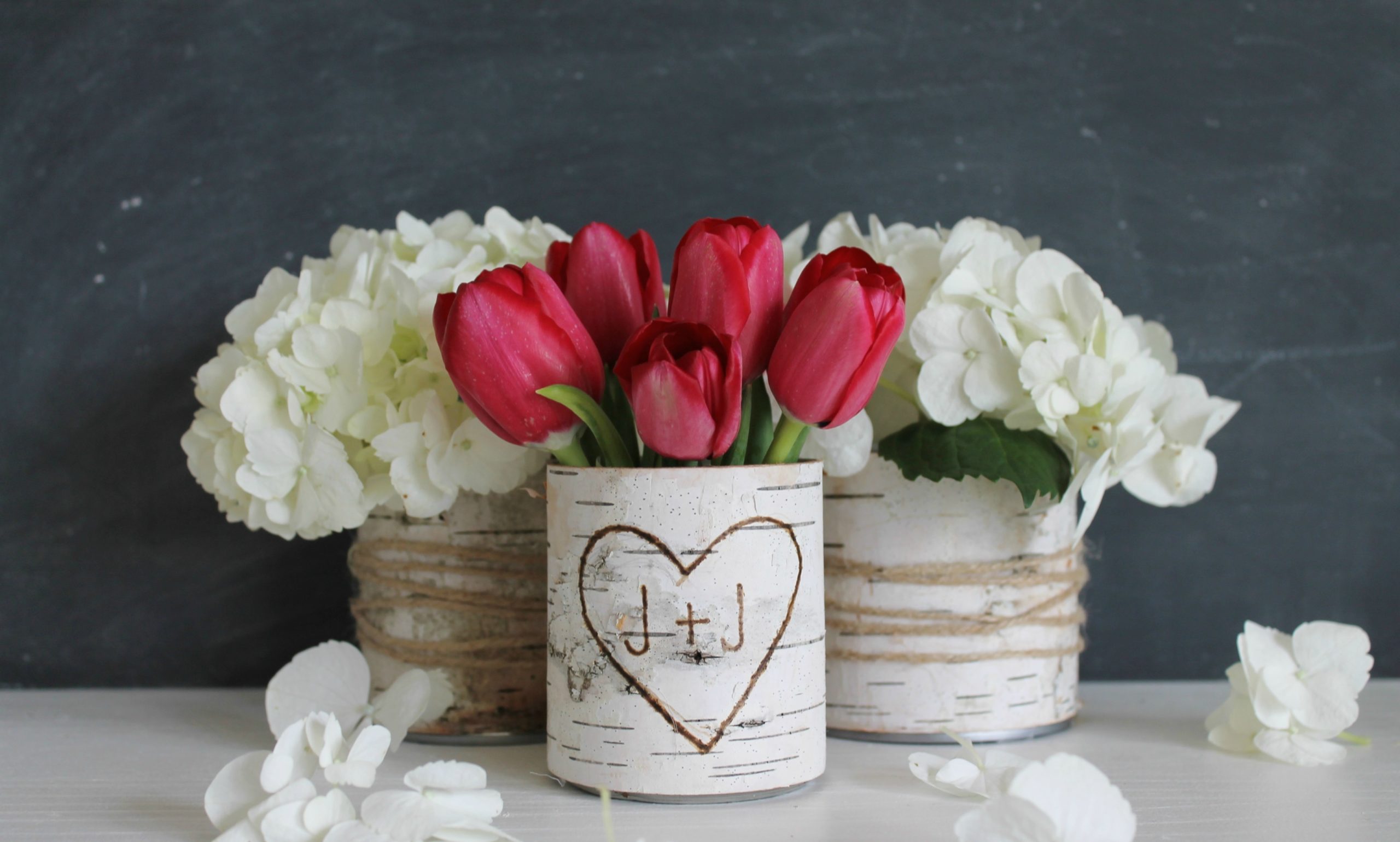 Red tulips in a carved vase in the middle of white flowers
