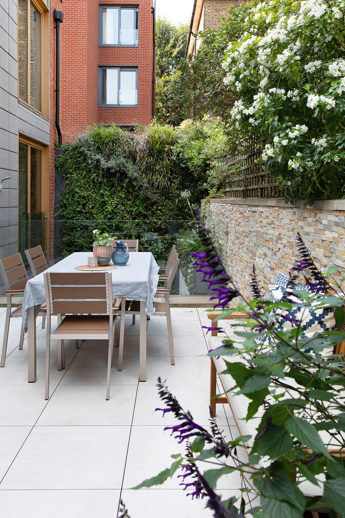 Small contemporary deck of London home with alfresco dining is surrounded by greenery