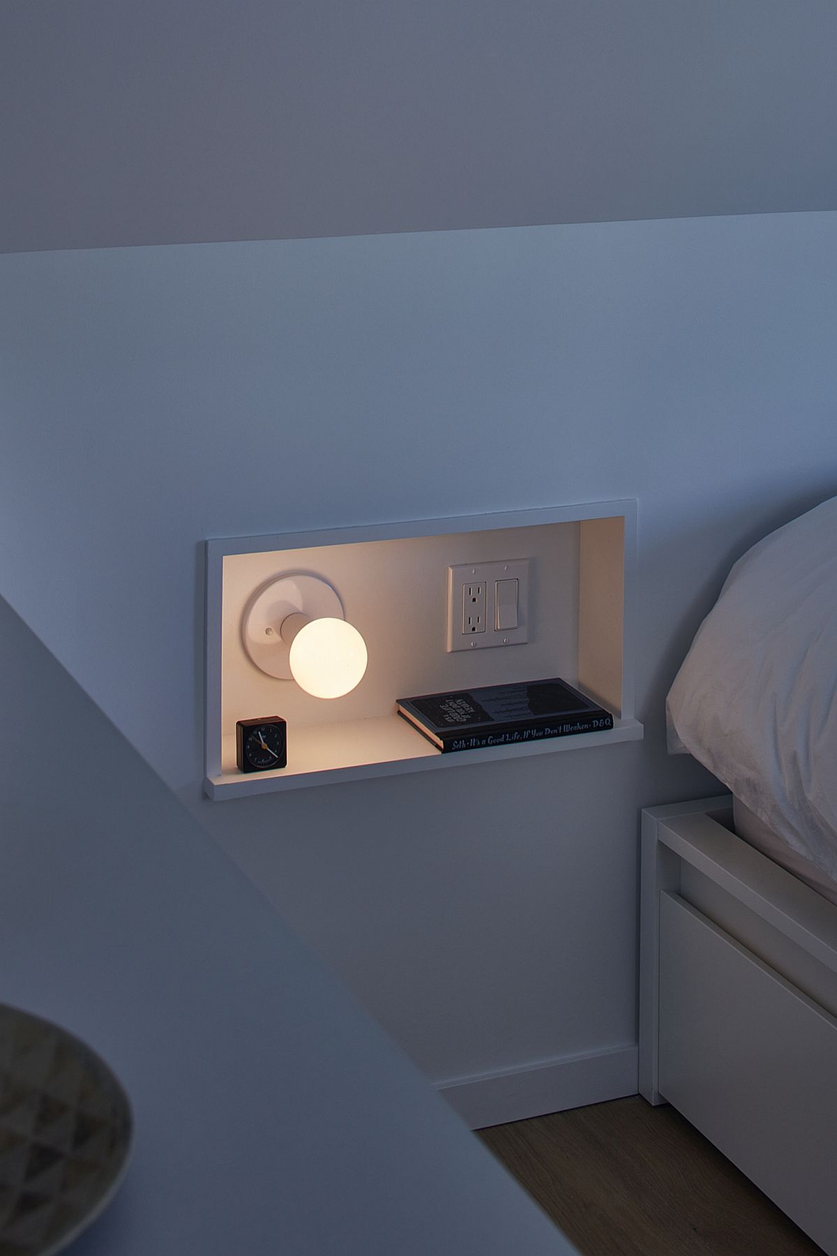 Small niche next to the bed inside the modern bedroom with space for a book and bed lamp