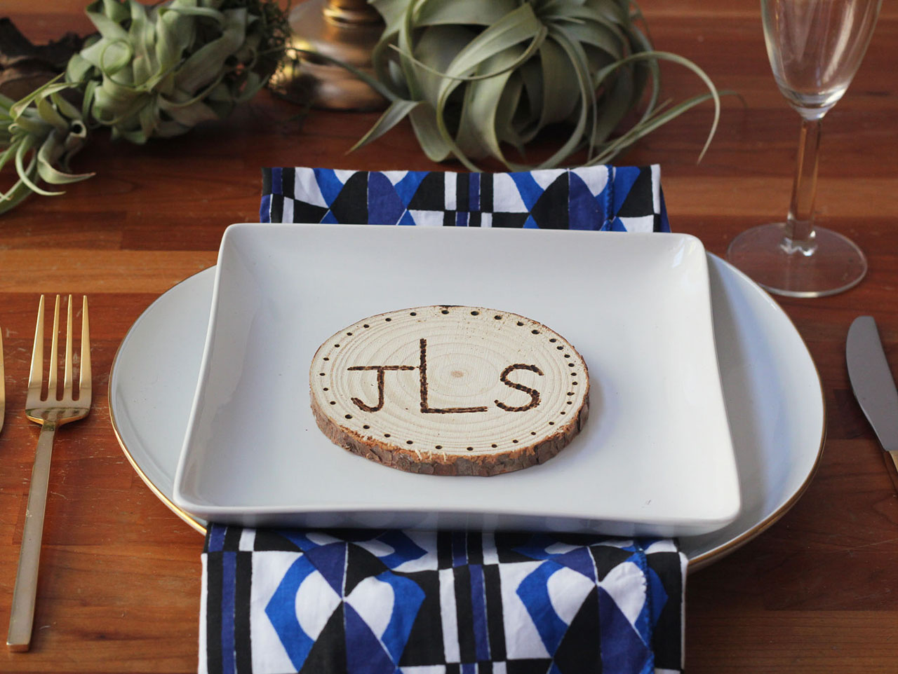 Table setting with wooden placecard on top of a white square plate