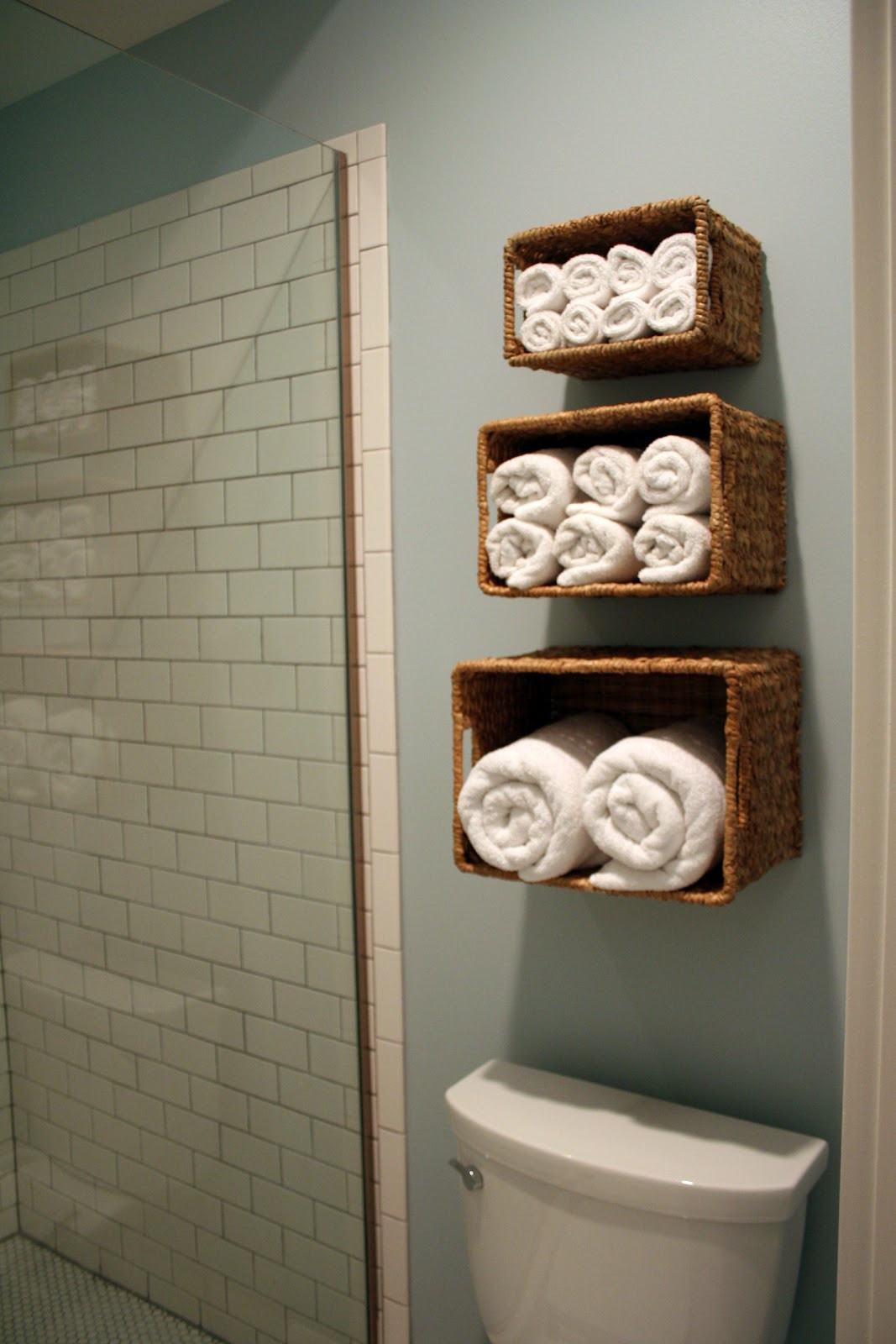 Three wicker baskets on the wall full of white towels