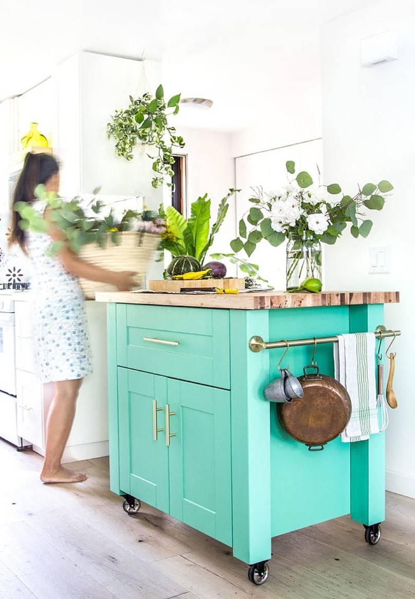 Utensils hanging on the side of green cabinet