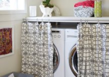 Washer and dryer hidden behind drapes and galvanized laundry cart