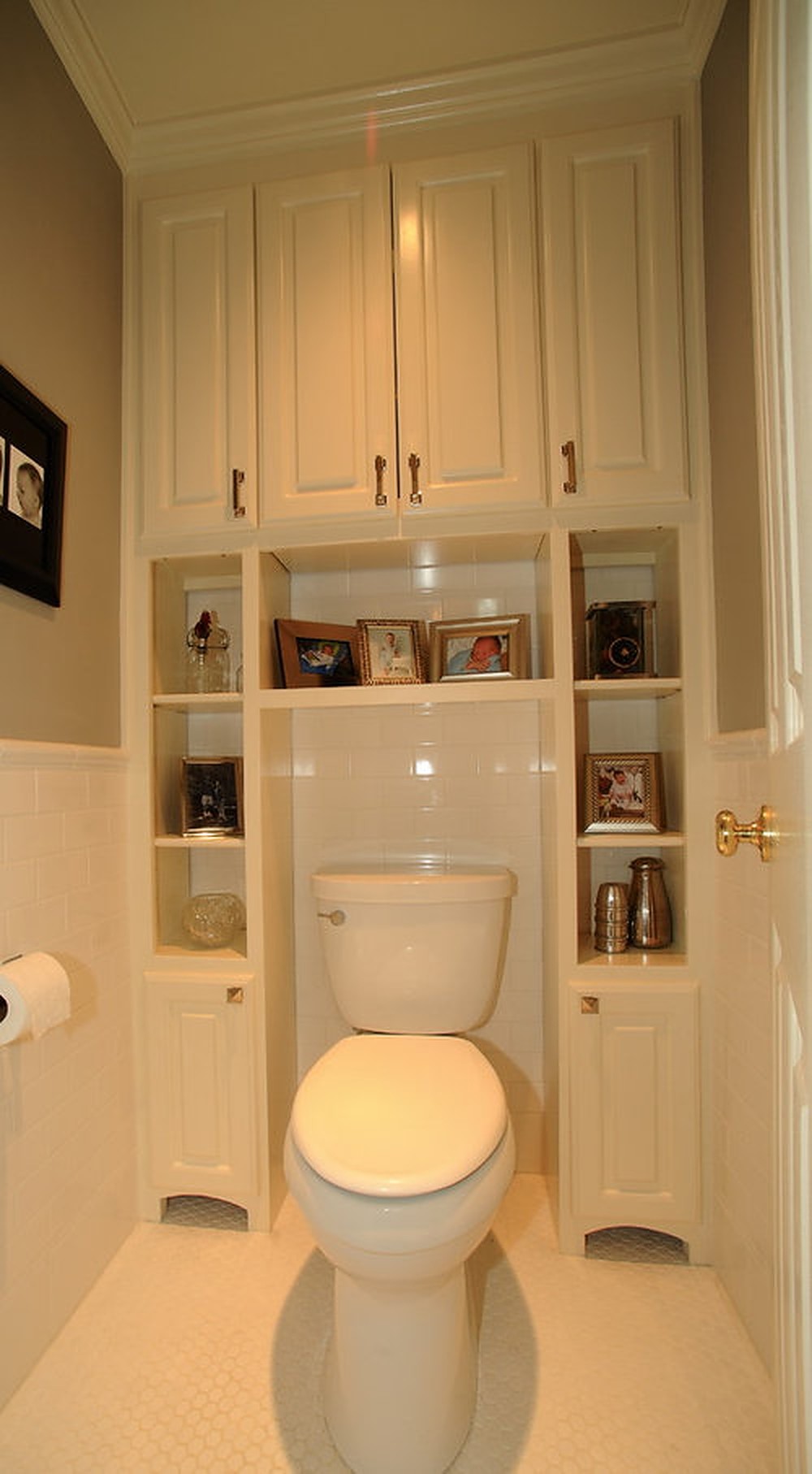 White cabinet with photos surrounding a white toilet