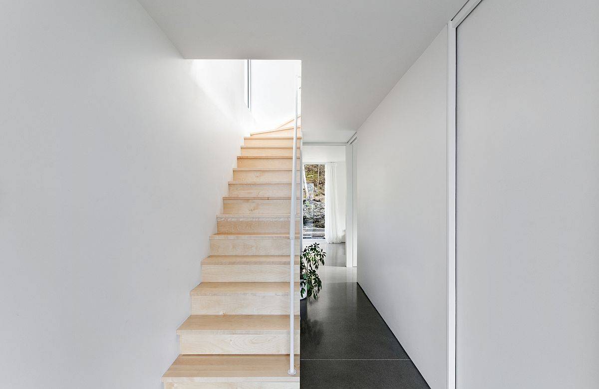 Wooden staircase brings warmth and elegance to the white interior of the home