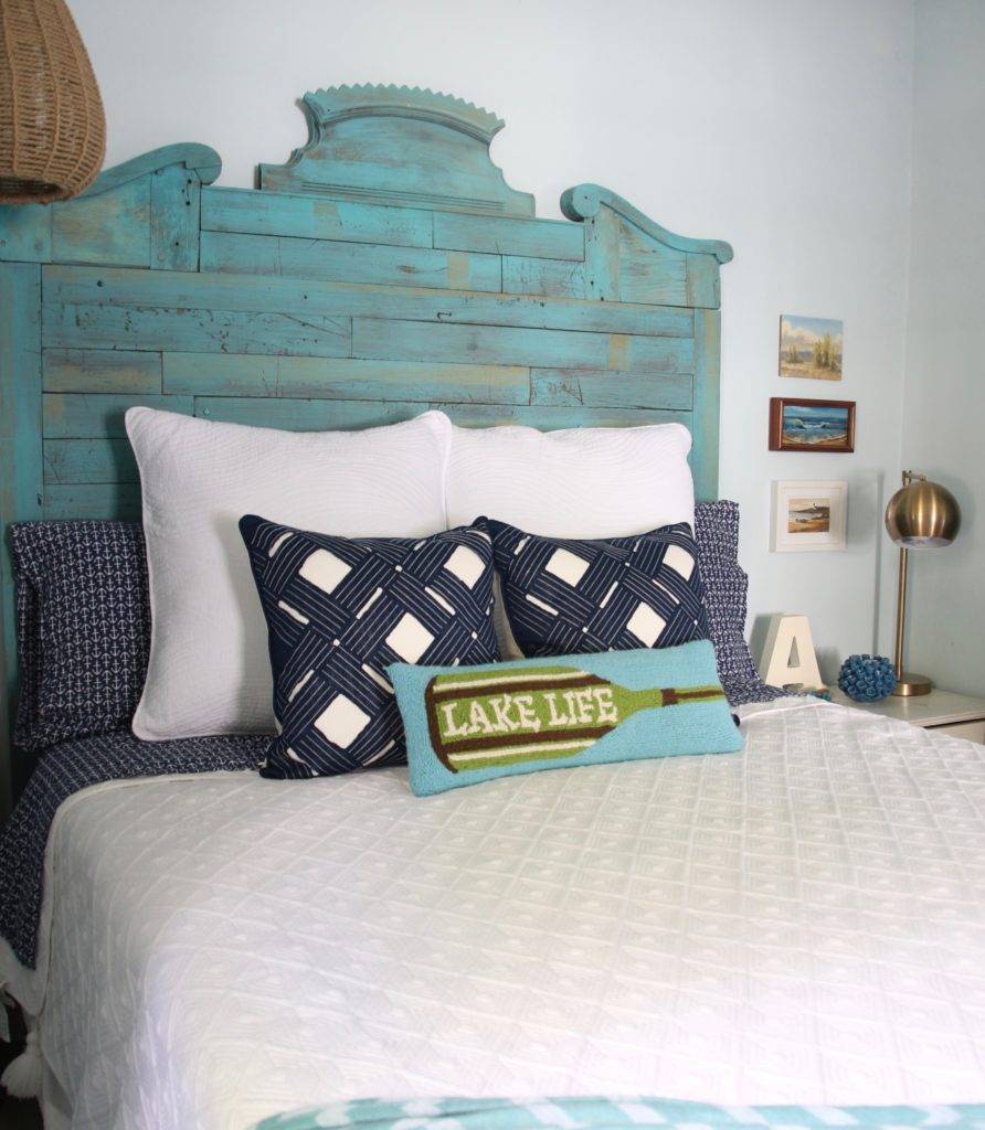 Bed with reclaimed headbord and blue and white pillows