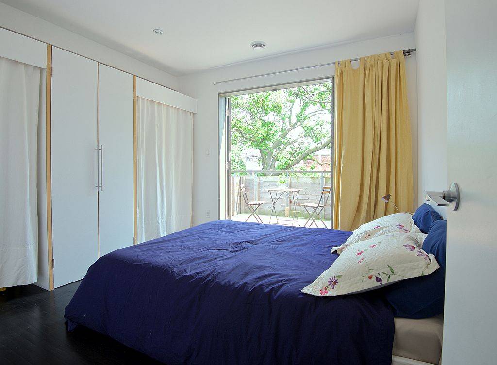 Bedroom in white with sliding glass doors accentuated by pops of yellow and blue