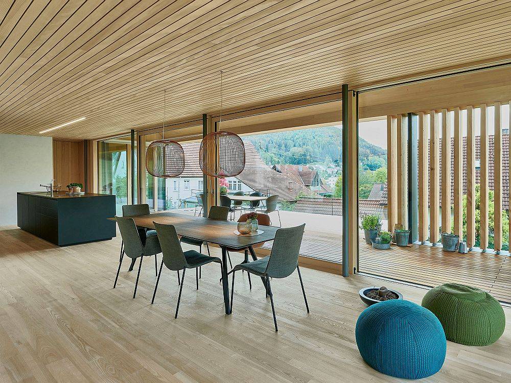 Black kitchen island and dining table add contrast to the open woodsy interior