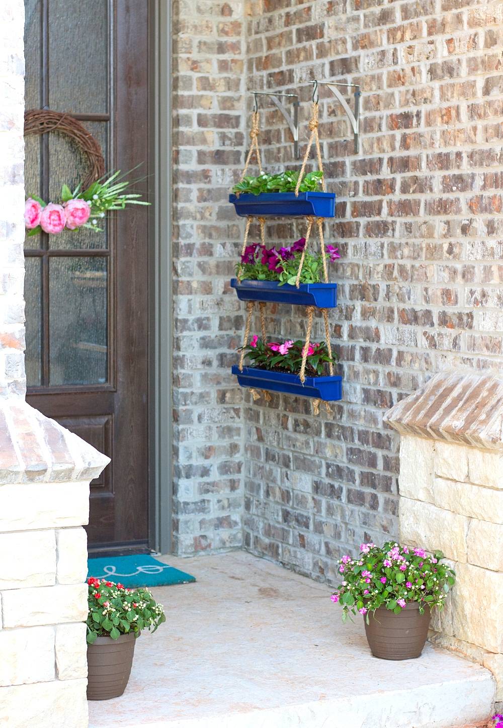 Blue hanging rain gutter planters on brick wall