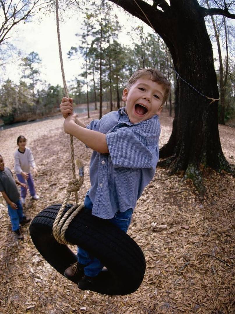 Boy standing on a tire hanging from the tree