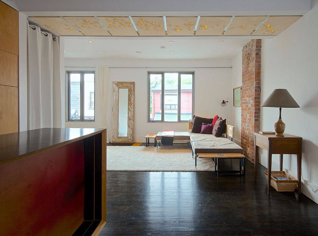 Brick wall section coupled with custom ceiling and a white backdrop inside the living room