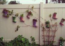 Colored boots hanging on white fence with vines