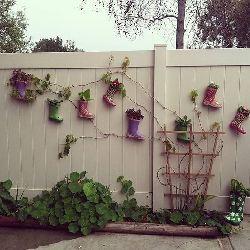 Colored boots hanging on white fence with vines