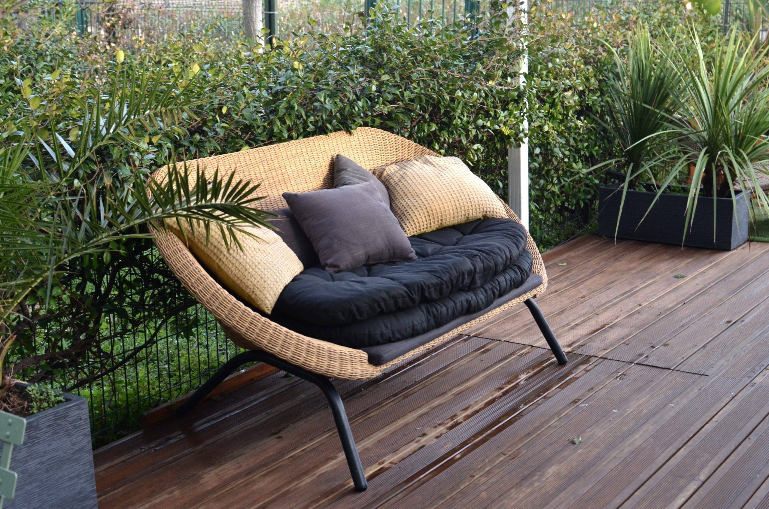 Cozy rattan sofa with cushions in tropical garden