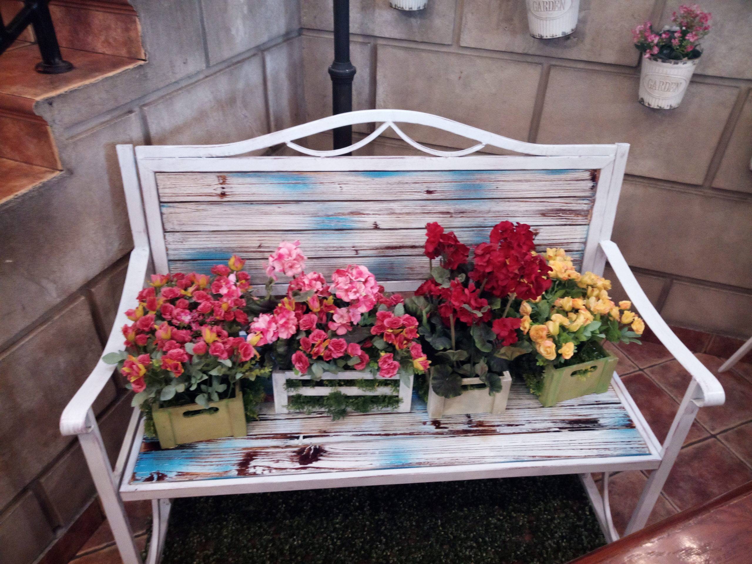 Flowers in square boxes on top of white bench