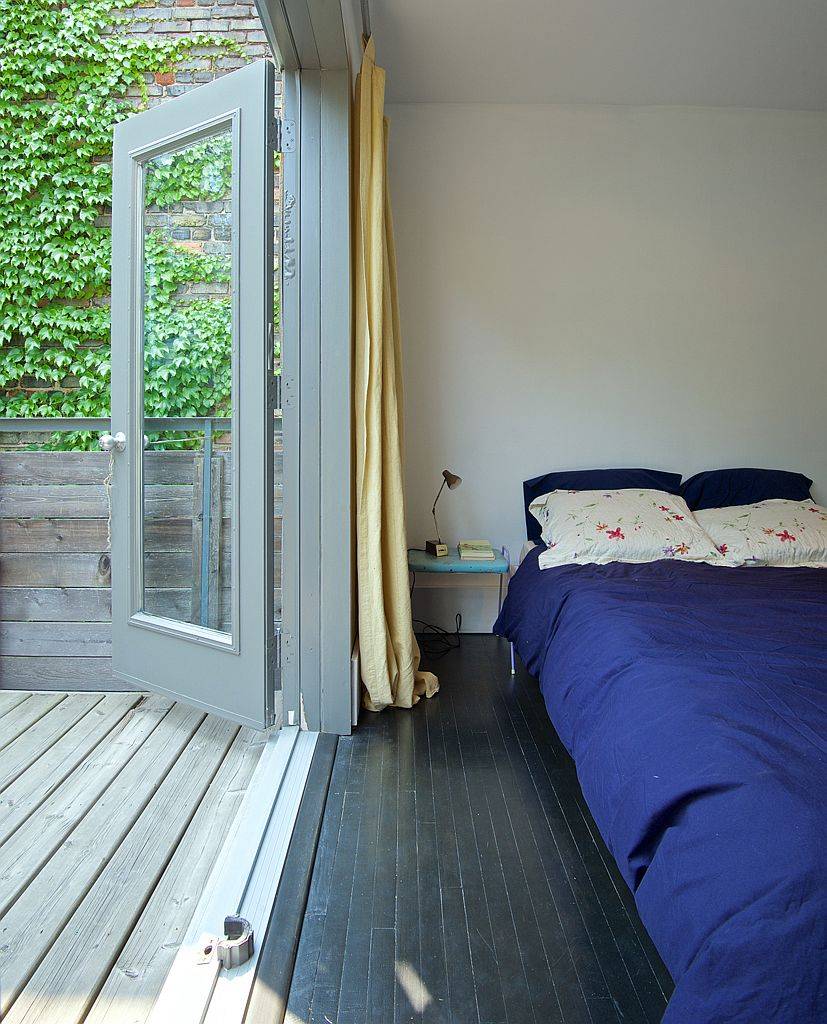 Folding glass doors swing open to connect the bedroom with the deck