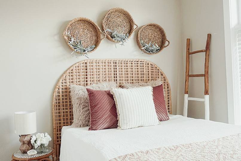 Half-painted wood ladder beside a bed with three wicker baskets above
