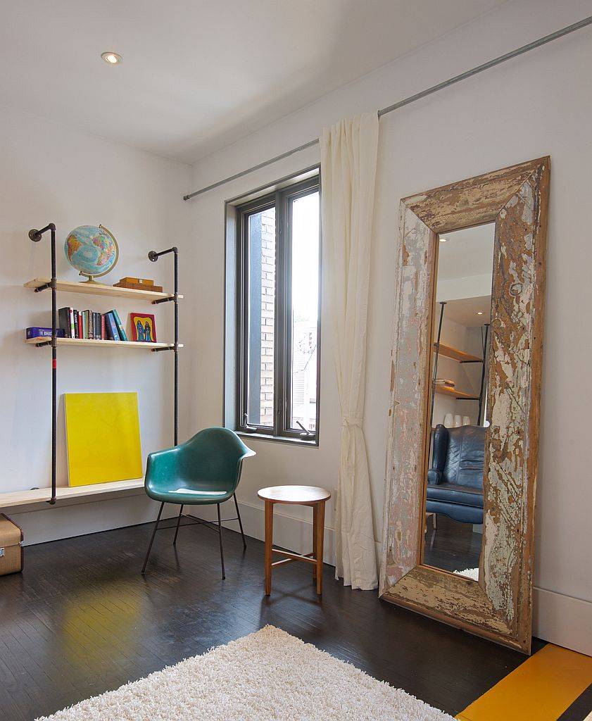 Large mirror with wooden frame on the floor is used as a decorative piece in the living room