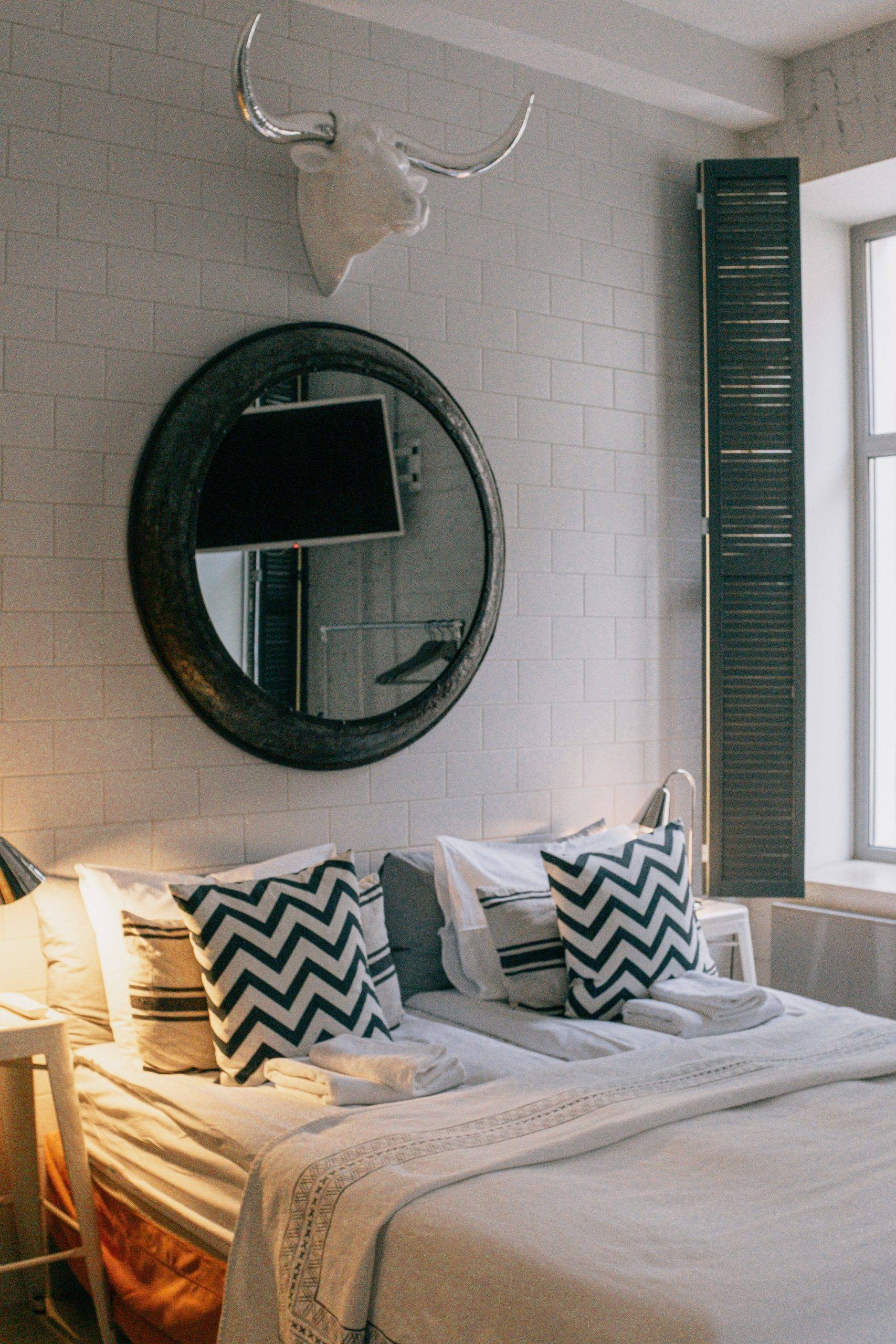 Large round mirror and bull head on the wall above the bed