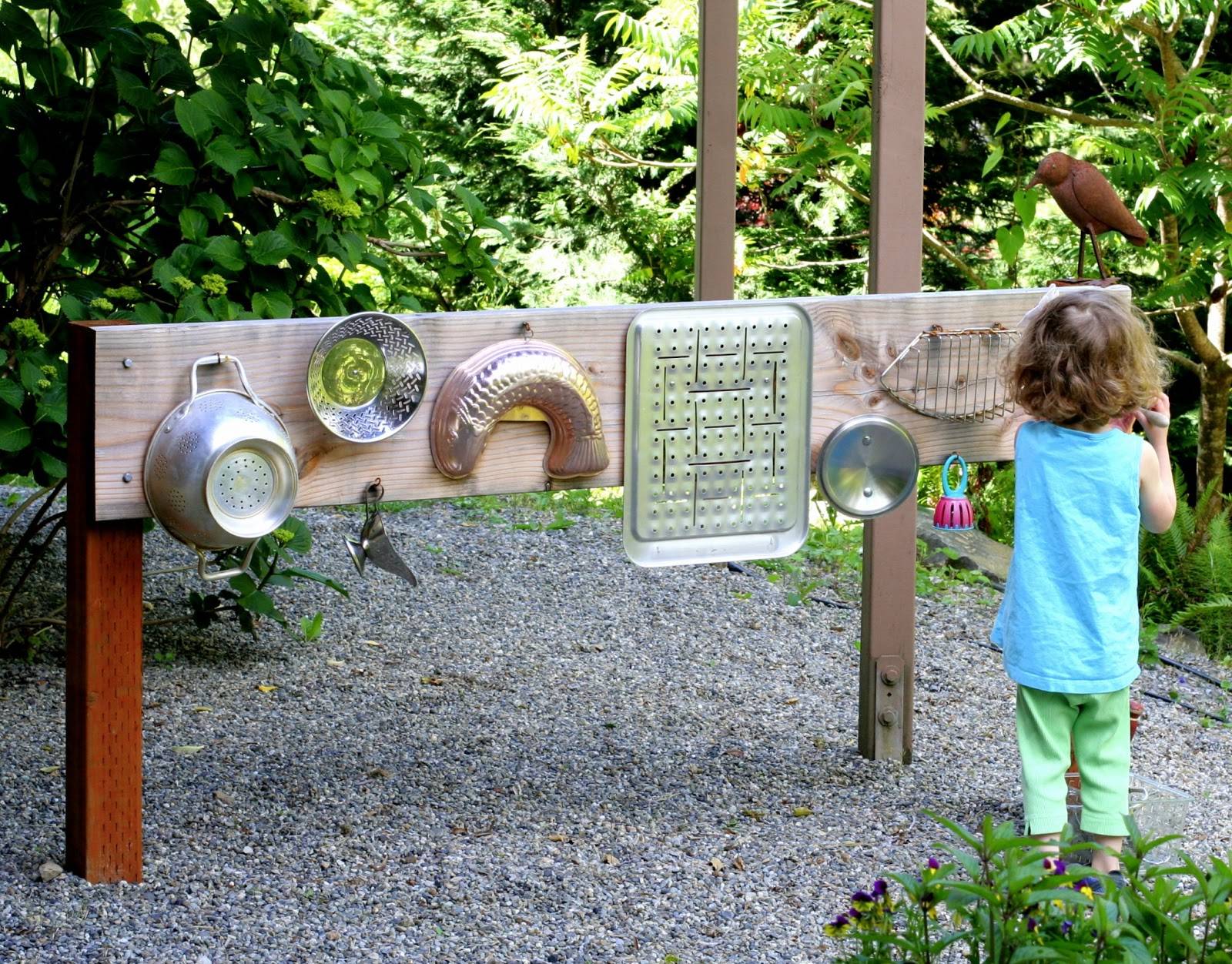 Little girl in blue facing different metal wares hanging on a wood