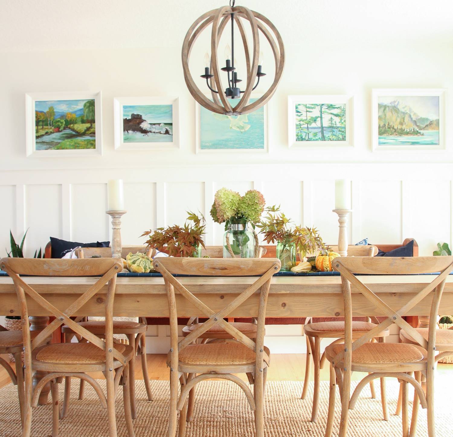 Long wood table with plants and candles at the center