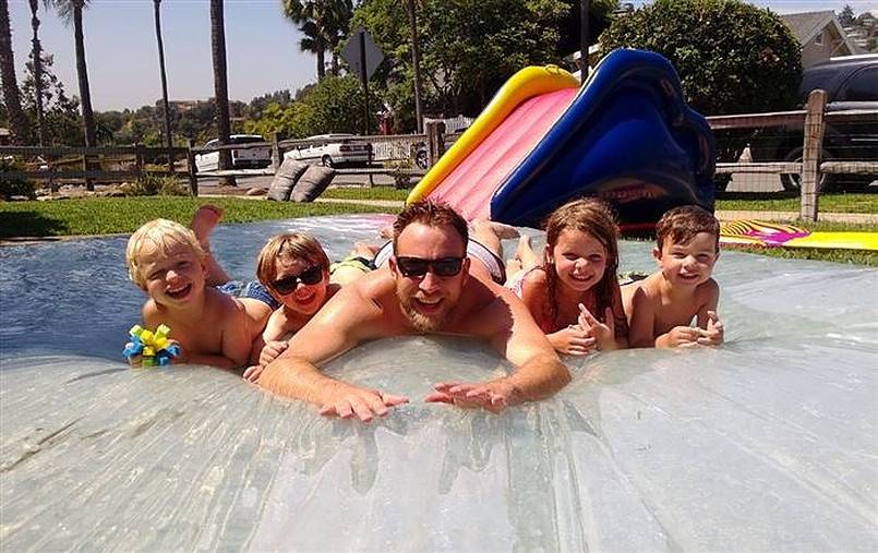 Man and kids on a water blob with small slide