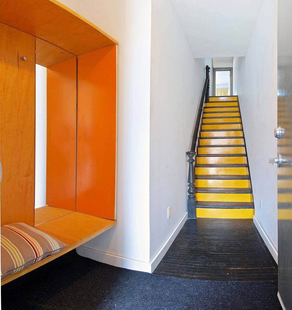 Modern entry with bench and a colorful splash of orange inside the Toronto home