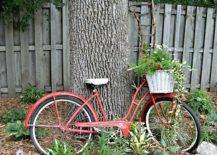 Old red bike leaning against a tree