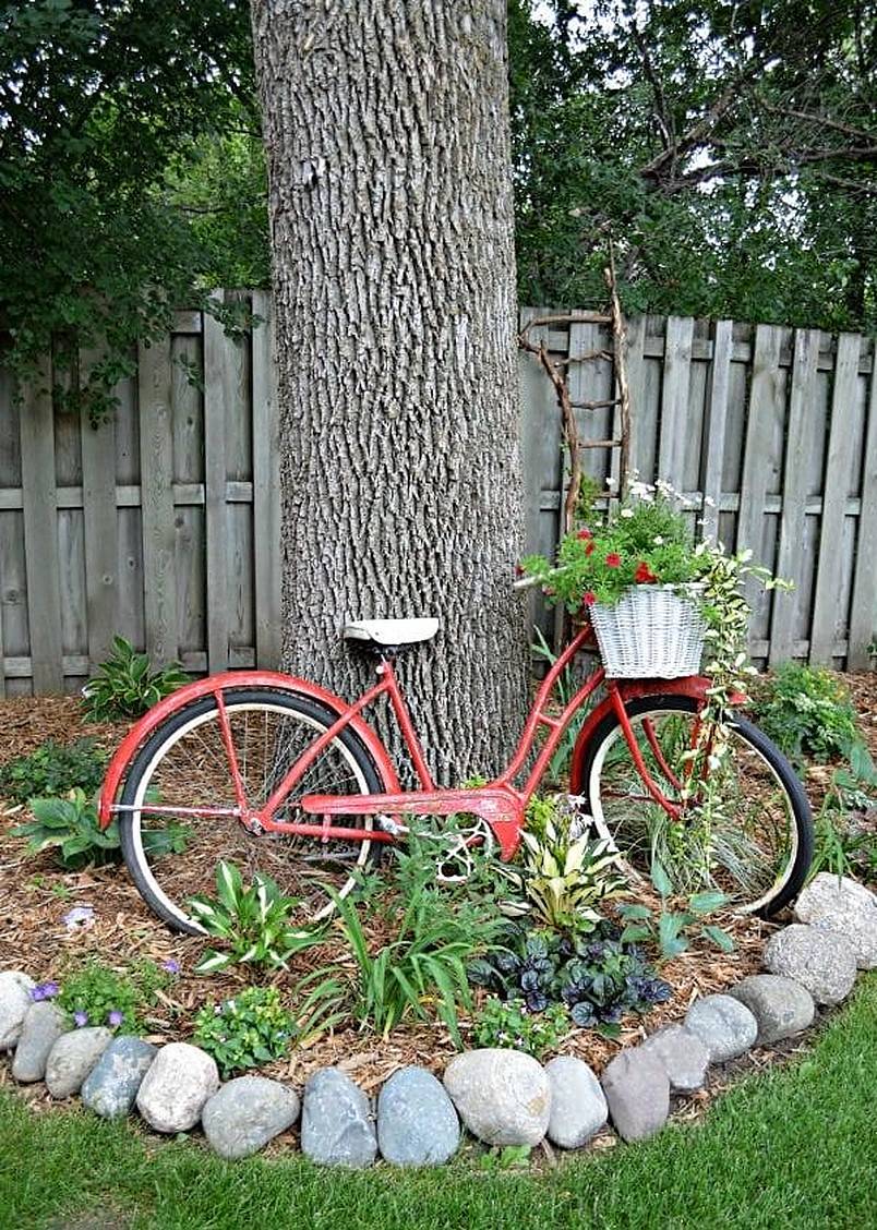 Old red bike leaning against a tree