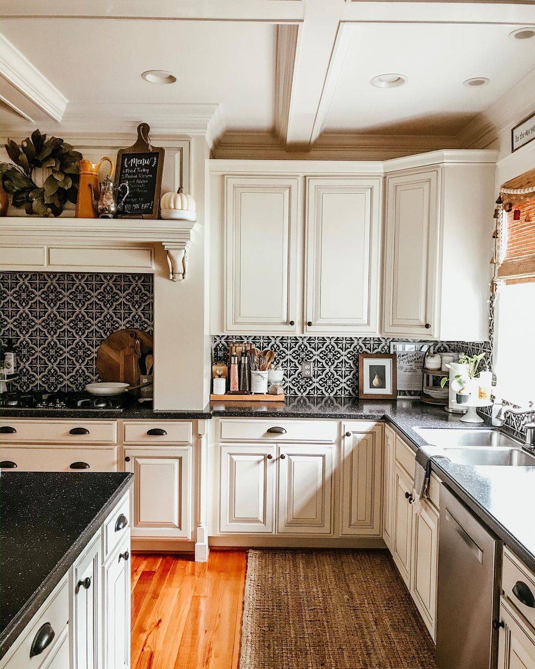 Patterned tiles in kitchen wall with white cupboards