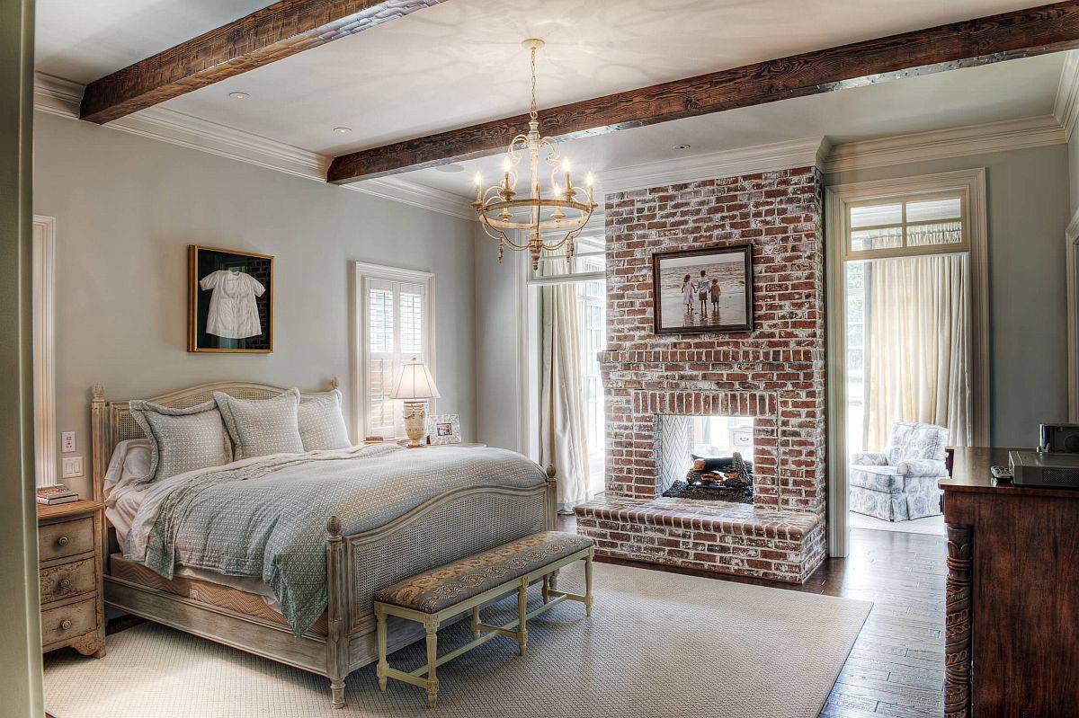 Picture-perfect traditional bedroom with wooden beams pastel hues and stylish brick fireplace