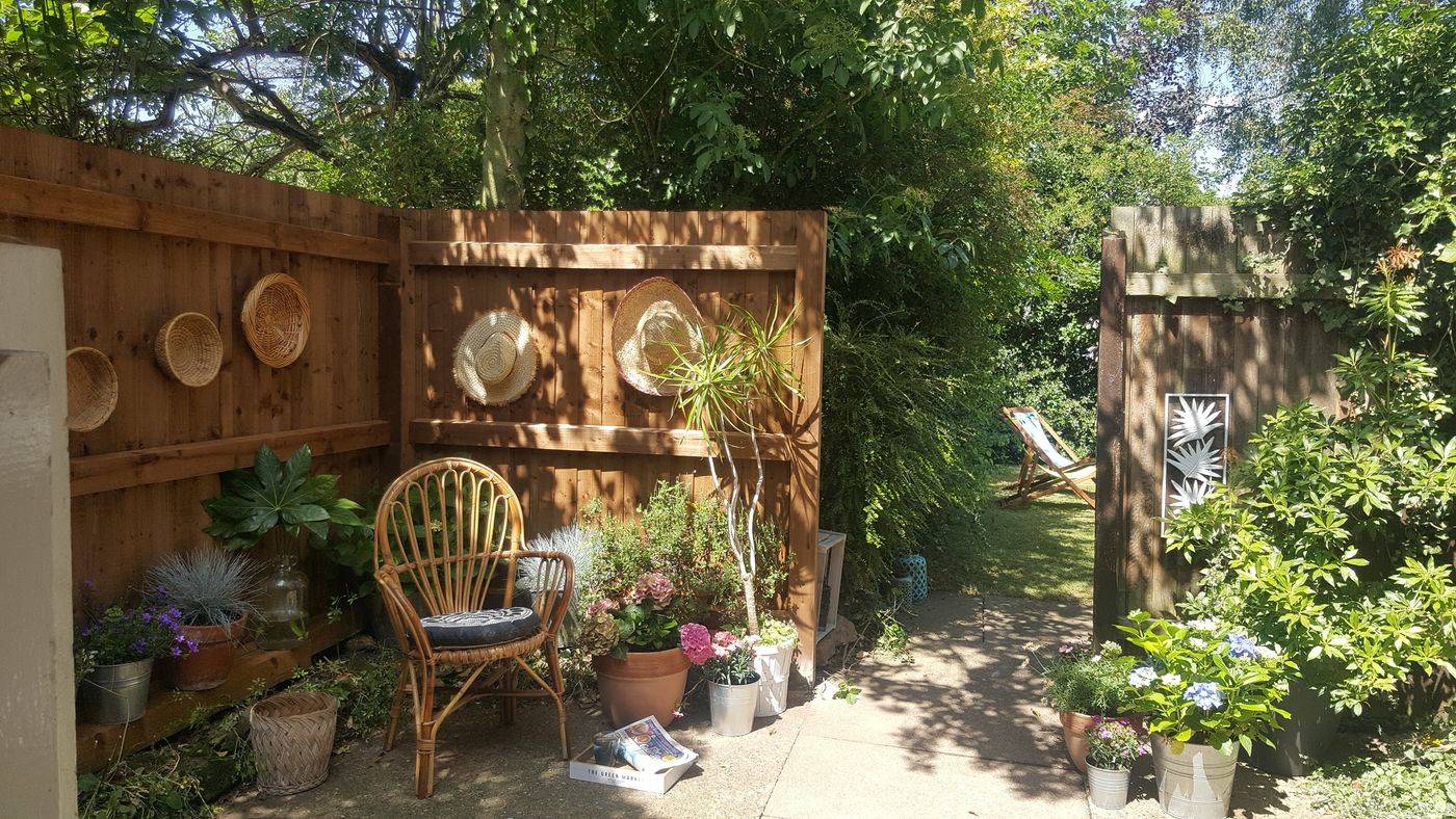 Walled garden with rattan baskets, hats and wicker chair