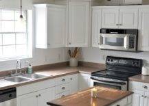 White cabinetry in kitchen with one candle on counter